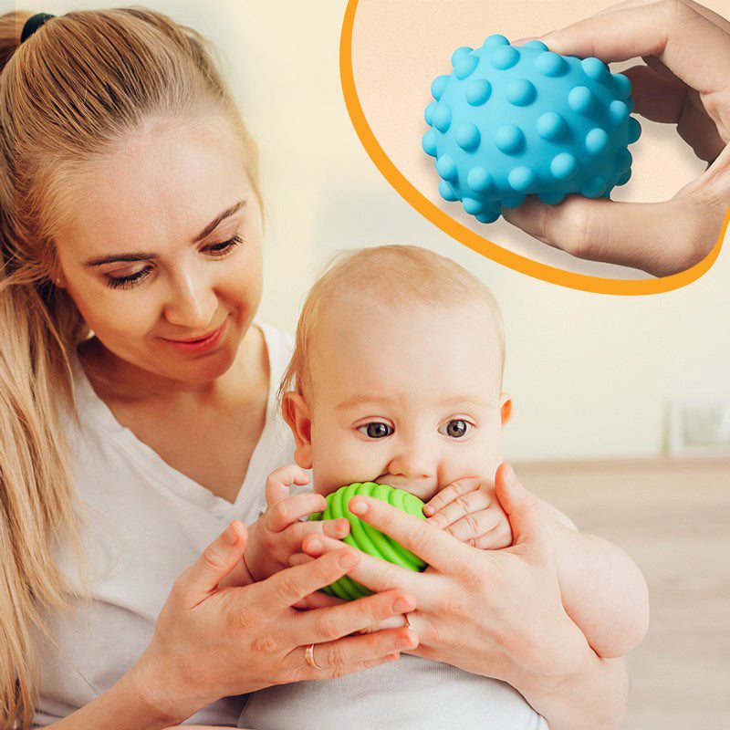Baby playing with textured sensory balls from Montessori Busy House toy for fine motor skills development