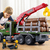 Child playing with oversized timber transport toy truck featuring a red crane and loaded with plastic logs