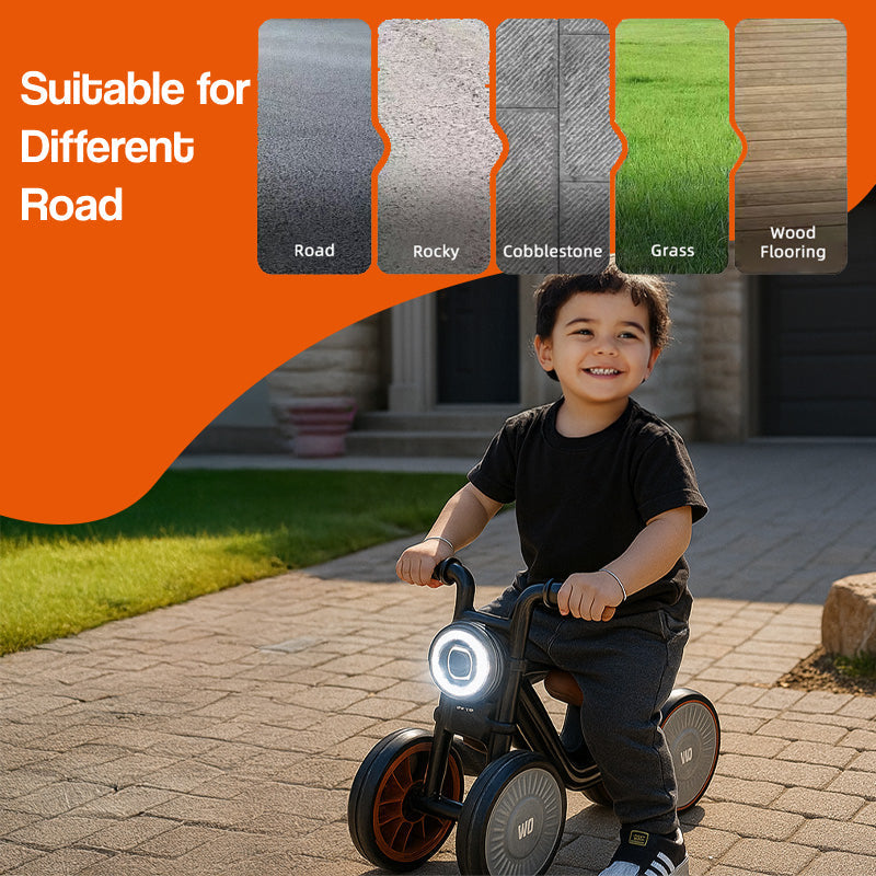 Toddler riding Tiny Biker Anti-Tip Light & Sound Motorcycle on cobblestone with illuminated front light, suitable for various road surfaces
